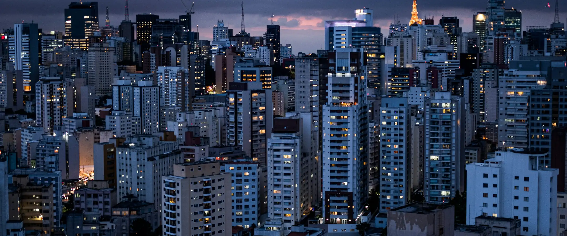 Prédios de São Paulo ao anoitecer, com as luzes acesas