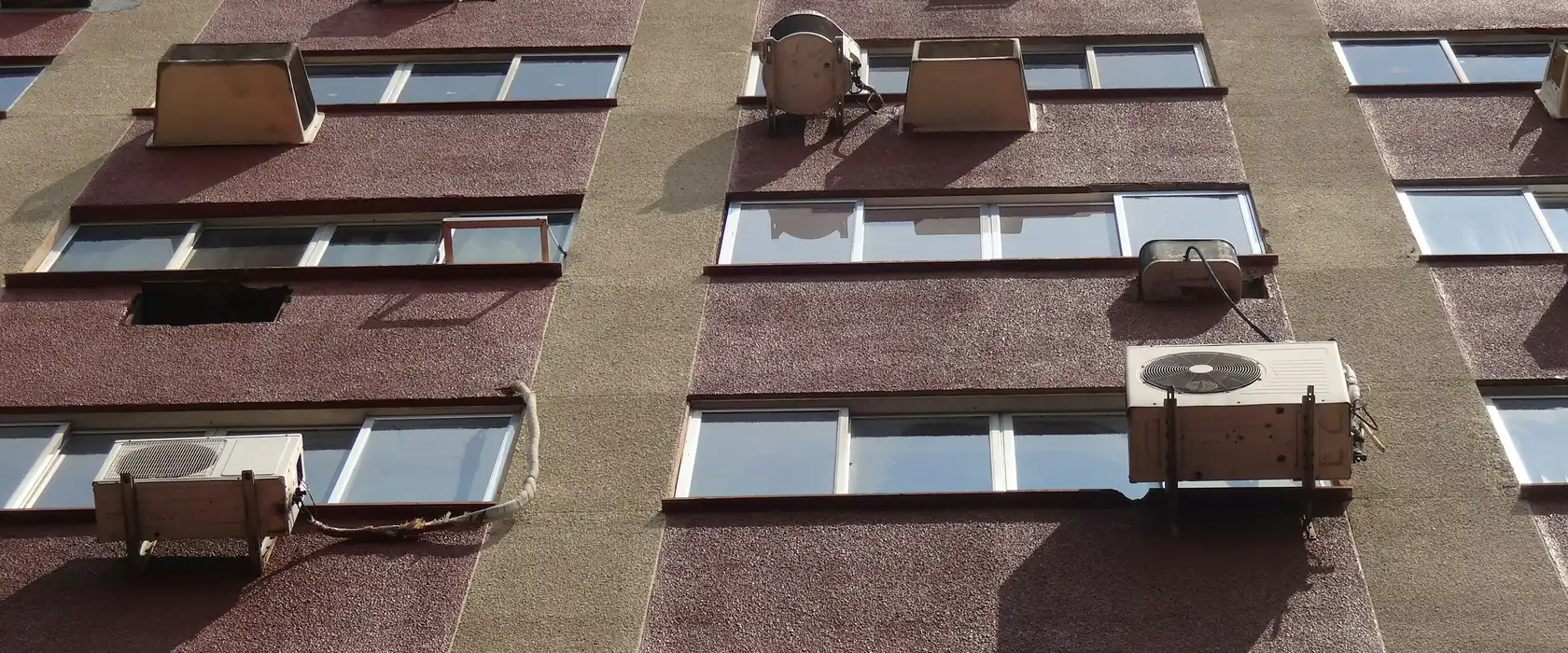 Fachada de prédio residencial com aparelhos de ar-condicionado nas janelas