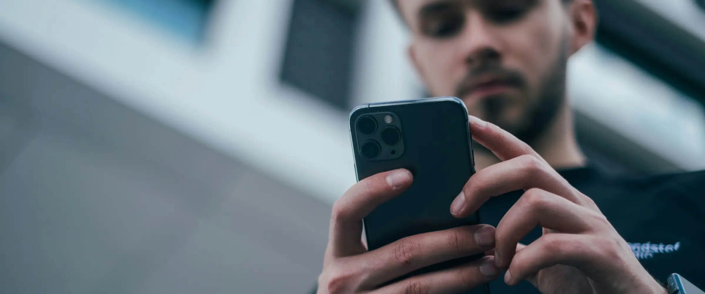 Homem usando o celular em frente a um prédio